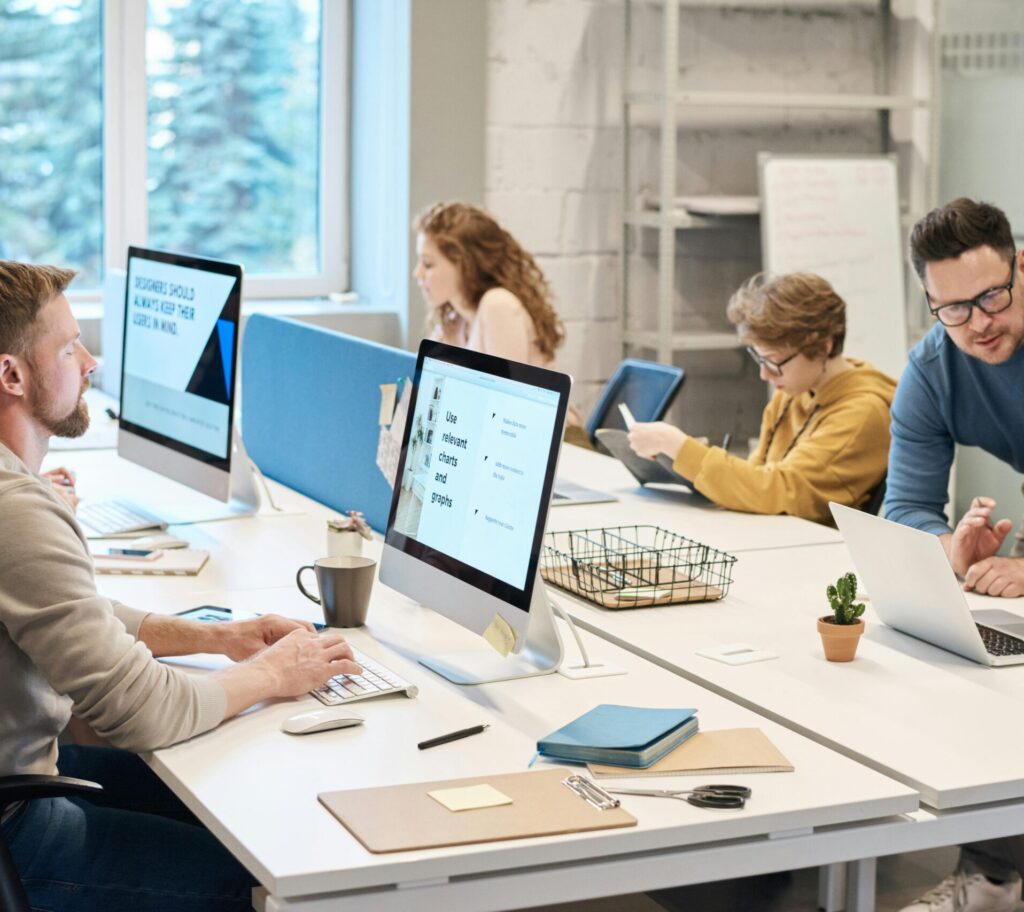 Team collaboration in a modern office setting with computers and diverse employees working together.