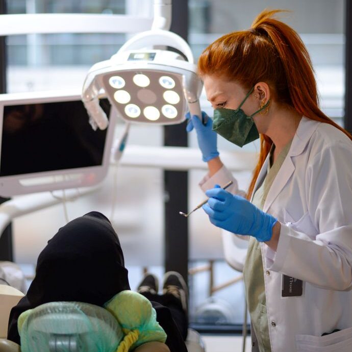 A female dentist in a modern clinic performing a dental procedure on a patient.